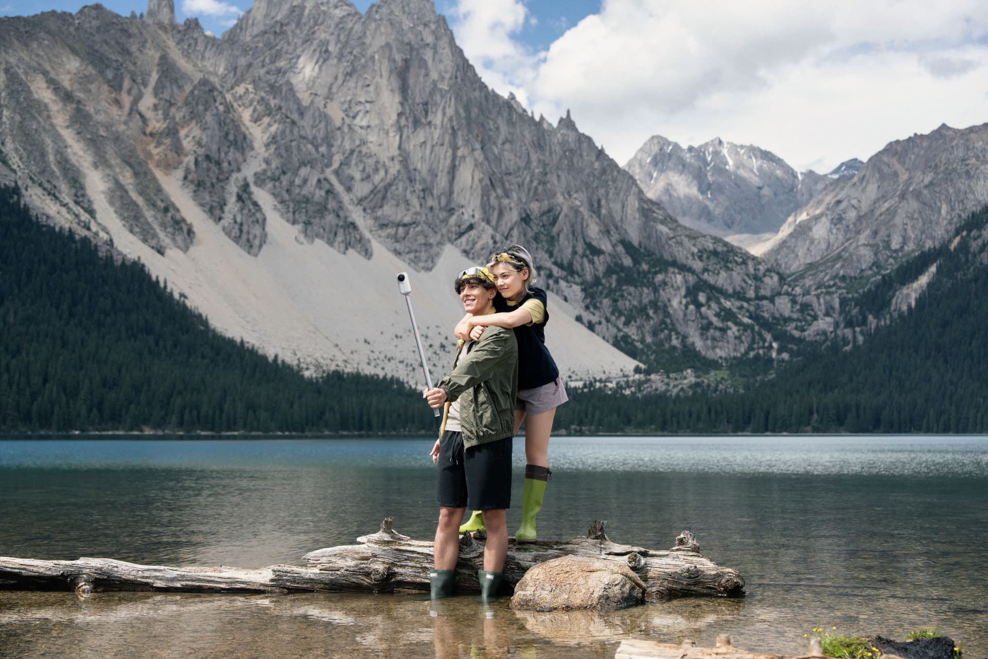 Couple standing on a log in a mountain lake filming with the X6